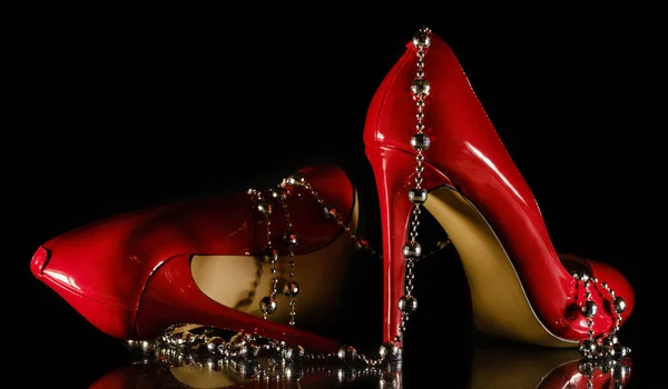 Patent leather shiny female red stilettos and beads on a black b — 图库照片