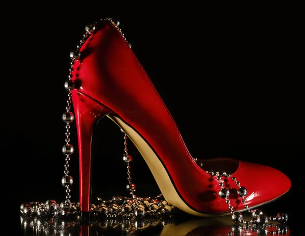 Patent leather shiny female red stilettos and beads on a black b — 스톡 사진