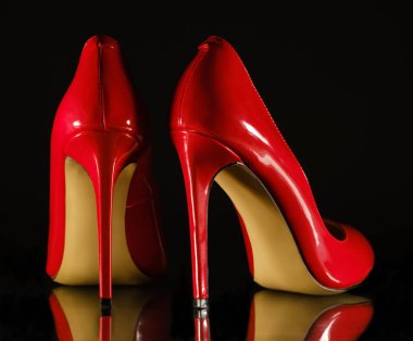 patent leather shiny female red stilettos on a black background
