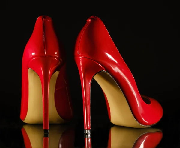 Patent leather shiny female red stilettos on a black background — 스톡 사진