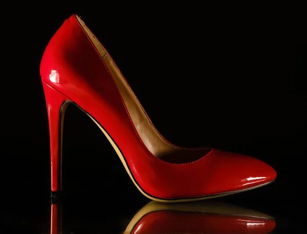 Couro envernizado estiletes vermelhos femininos brilhantes em um fundo preto — Fotografia de Stock