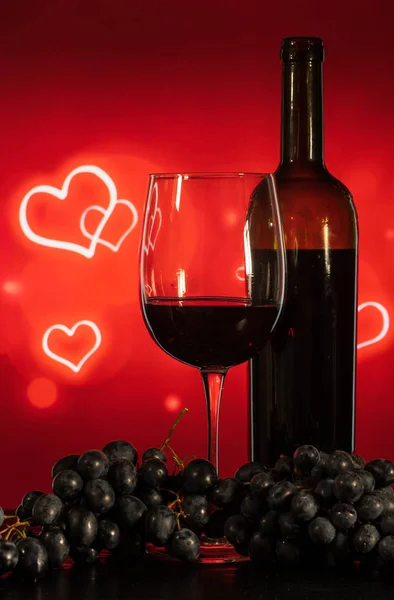 Copa con vino y uvas sobre fondo rojo con corazones —  Fotos de Stock
