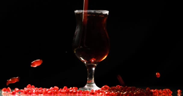 Glass with pomegranate juice and falling pomegranate seeds on a black — Stock Video