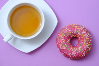 Kremalı güzel bir çörek ve bir fincan çay. Mor bir grupta.