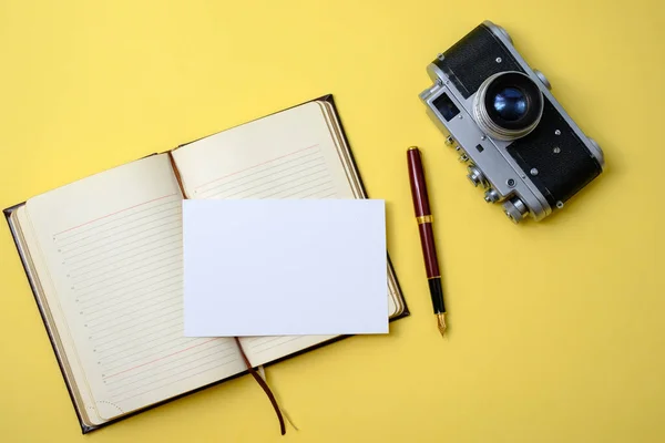 美しい古いヴィンテージレトロカメラペンと写真カード付きの日記黄色の背景 — ストック写真