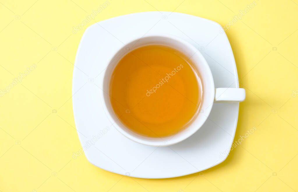 beautiful white cup with tea on a yellow backgroun