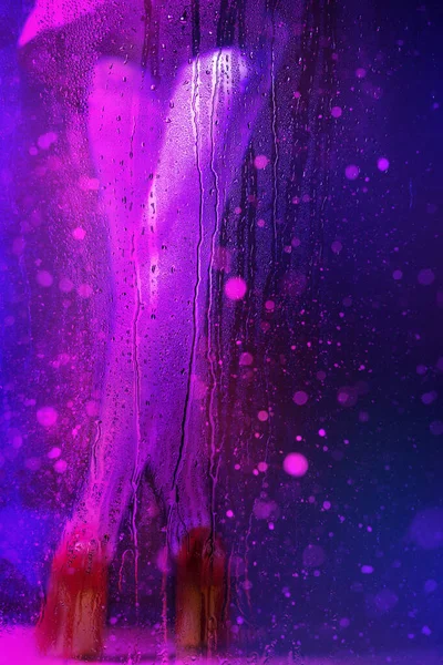雨滴在湿玻璃杯后的霓虹灯下 美丽而模糊的女性腿 — 图库照片