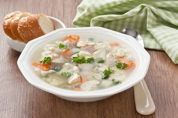 Суп с курицей, цветной капустой, овощами и хлебом в белой тарелке — стоковое фото