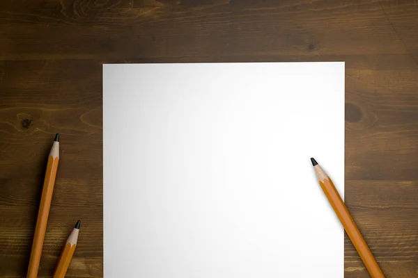 Pencils with white paper on wooden table — Stock Photo, Image