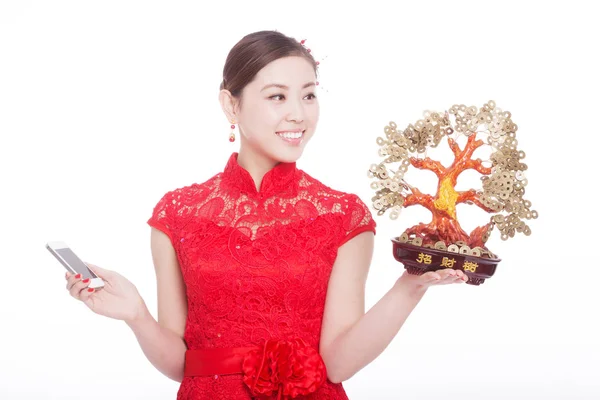Mujer sostiene el teléfono móvil y el árbol de la suerte en año nuevo chino — Foto de Stock