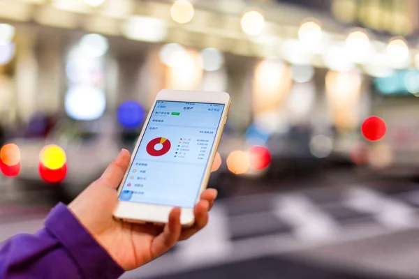 Kvinna söker aktiemarknaden i mobiltelefon — Stockfoto