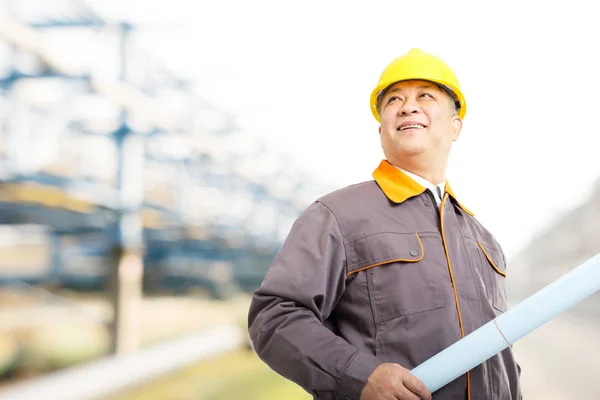 engineer with blueprint on oil refinery plant