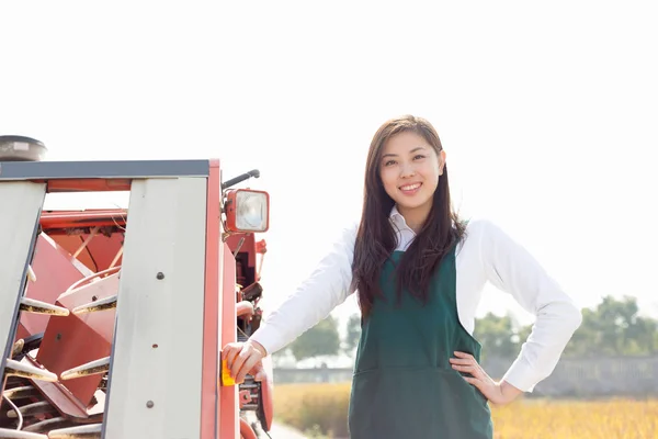 Woman agronomist in cereal field with harvester — Stock Photo, Image