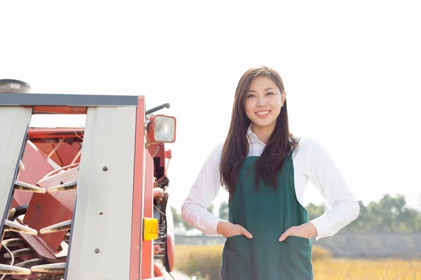 Woman agronomist in cereal field with harvester — Stock Photo, Image