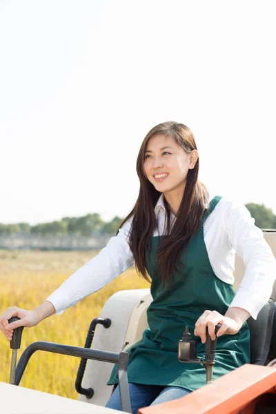 Vrouw agronoom in granen veld met harvester — Stockfoto