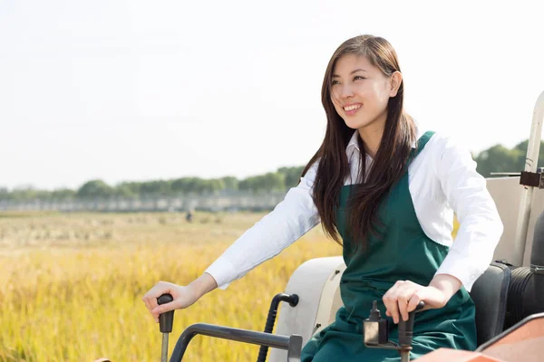 Woman agronomist in cereal field with harvester — Stock Photo, Image