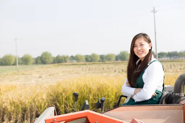 Woman agronomist in cereal field with harvester — Stock Photo, Image