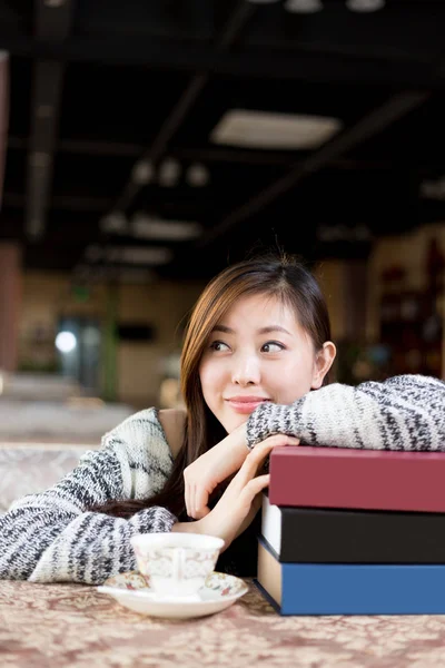 Young chinese woman with books in cafe — Stock Photo, Image