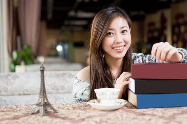Jonge chinese vrouw met boeken in café — Stockfoto