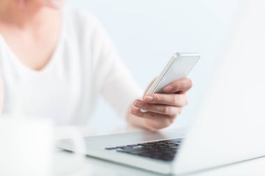 ofiste dizüstü bilgisayar ve cep telefonu kullanan kadın