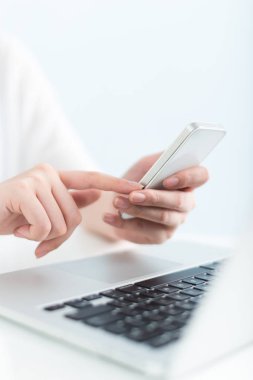 ofiste dizüstü bilgisayar ve cep telefonu kullanan kadın