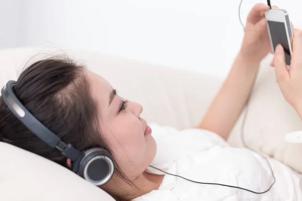 Kvinna på sängen lyssnar musik med mobiltelefon — Stockfoto