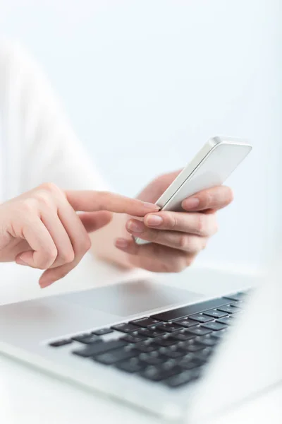 Mulher usando laptop e telefone celular no escritório — Fotografia de Stock