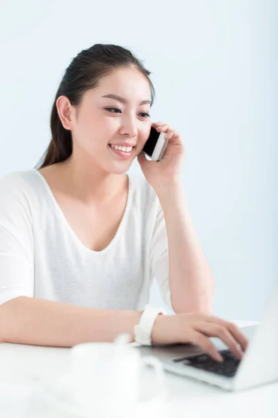 Vrouw met laptop en mobiele telefoon in office — Stockfoto