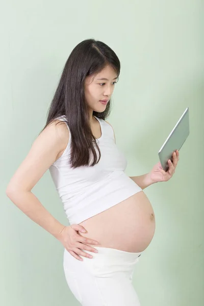 Молодая красивая беременная женщина с планшетом — стоковое фото