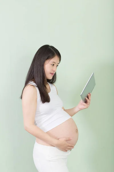 Jonge mooie zwangere vrouw met tablet — Stockfoto