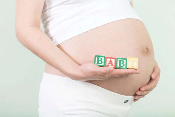 Jonge mooie zwangere vrouw met blokjes — Stockfoto