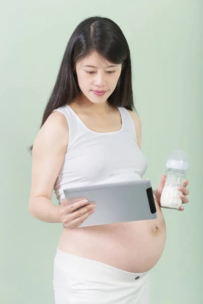 Zwangere vrouw houdt Tablet PC- en fles met melk — Stockfoto