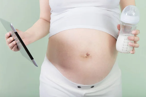 Pregnant woman holds tablet and bottle with milk — Stock Photo, Image