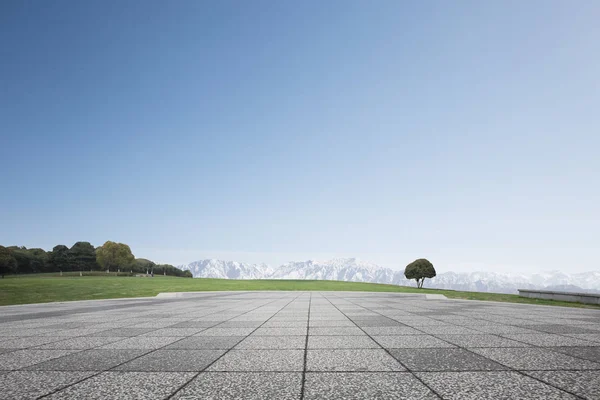 Empty brick floor with white snow mountains — Stock Photo, Image