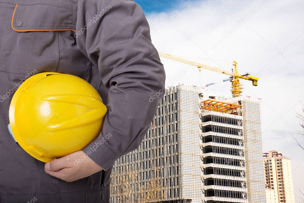 chinese man technician with yellow helmet standing front of constructions site