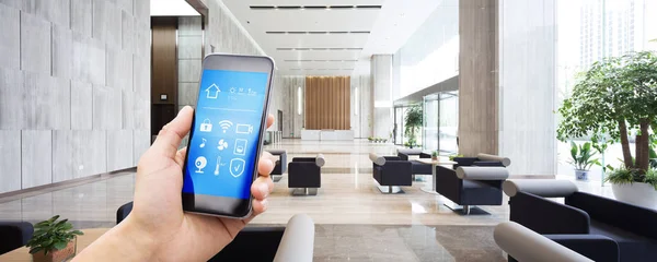 现代办公楼宽敞大厅内的智能家居手机与应用程序 — 图库照片