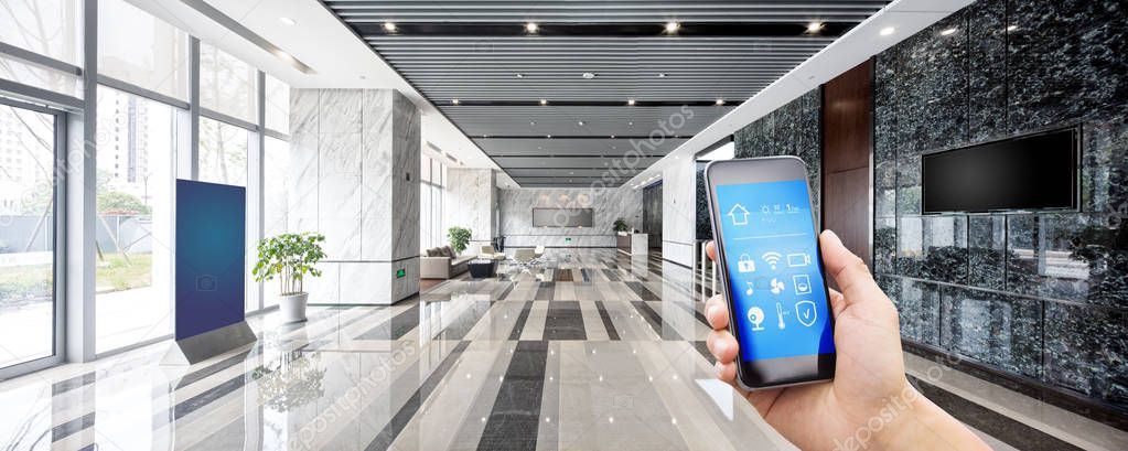 mobile phone with app on smart home in spacious hall of modern office building