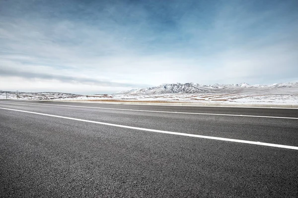 Camino de asfalto vacío con montañas de nieve —  Fotos de Stock