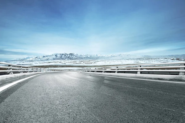 Camino de asfalto vacío con montañas de nieve — Foto de Stock