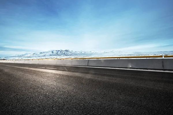 Empty asphalt road with snow mountains — Stock Photo, Image