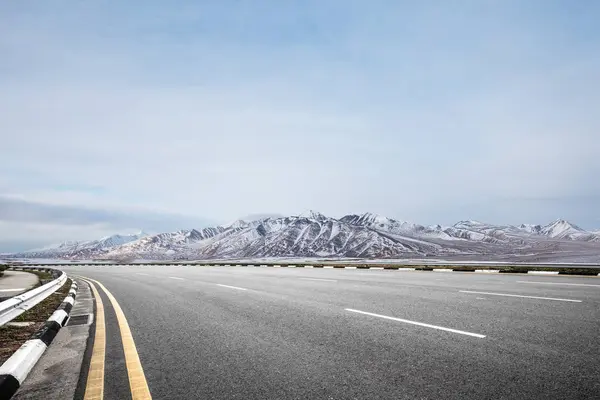 Leere Asphaltstraße mit Schneebergen — Stockfoto