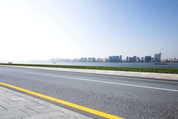 Strada asfaltata emtpy con paesaggio urbano — Foto Stock