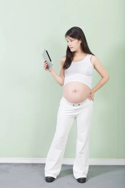 Young pretty pregnant woman with tablet — Stock Photo, Image
