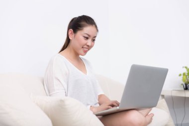 güzel kadın kanepede dizüstü bilgisayar kullanarak