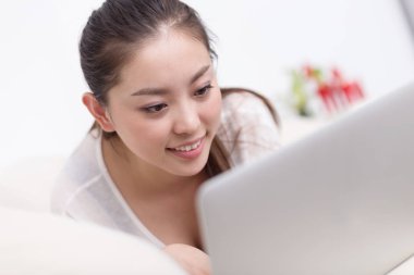 güzel bir kadın yatakta dizüstü kullanarak