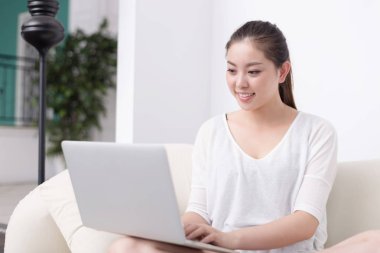 güzel kadın kanepede dizüstü bilgisayar kullanarak