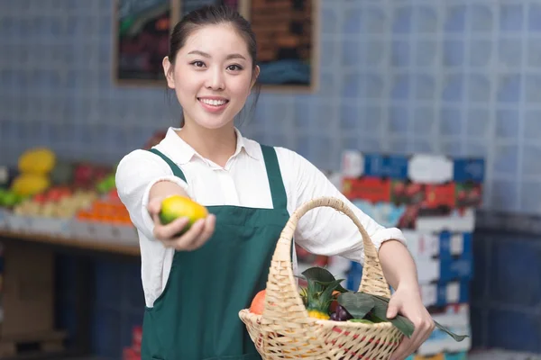 Pretty woman works in fruit store — Stock Photo, Image