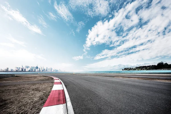 Camino vacío cerca del lago con paisaje urbano — Foto de Stock