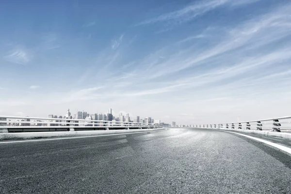 Empty road with cityscape near water — Stock Photo, Image