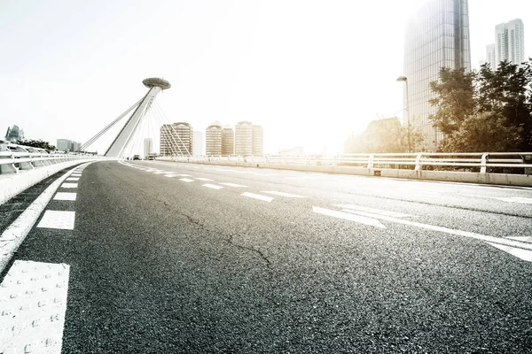 Strada asfaltata vuota sul ponte moderno con raggio di sole — Foto Stock